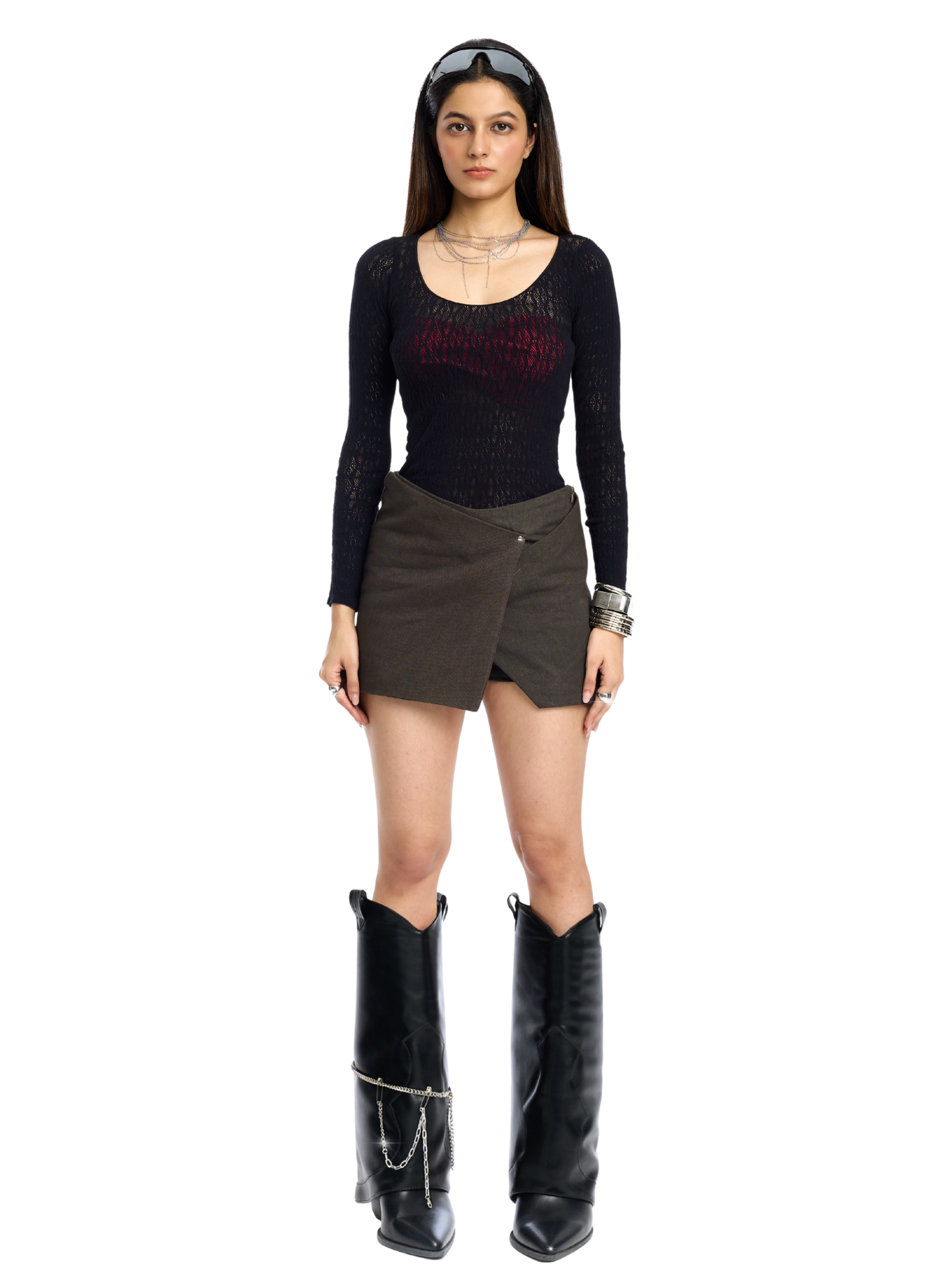 Woman wearing a black long-sleeve top, brown skirt, and black boots on a white background