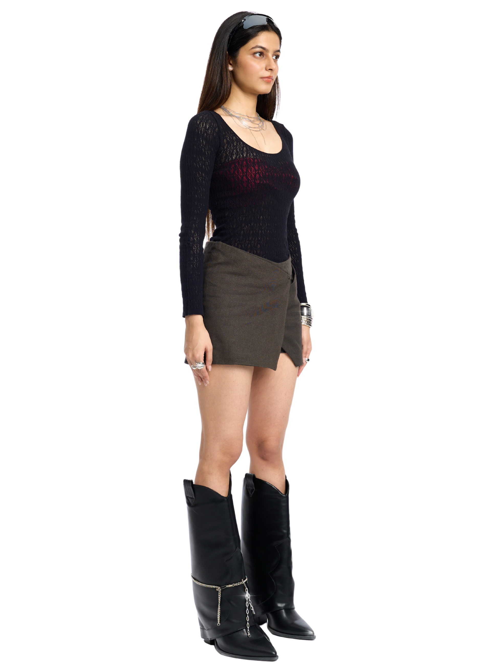 Woman wearing a black top, brown skirt, and black boots on a white background