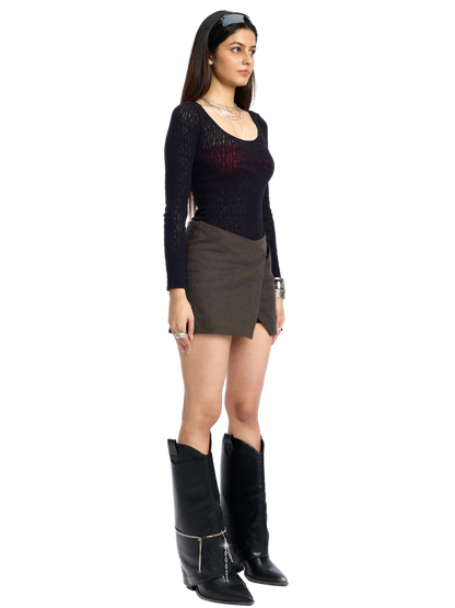 Woman wearing a black top, brown skirt, and black boots on a white background