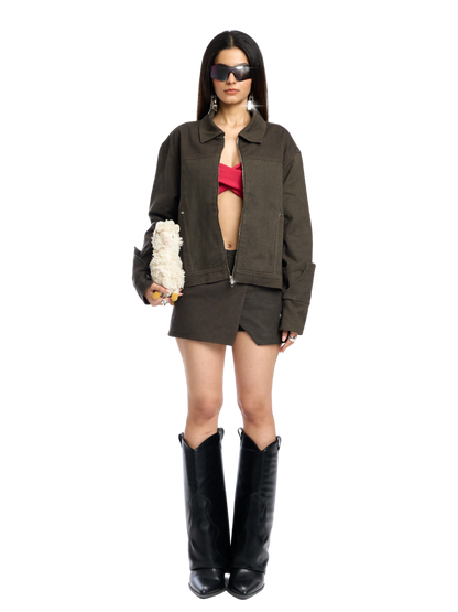 Woman wearing a green jacket, red top, and black boots on a white background
