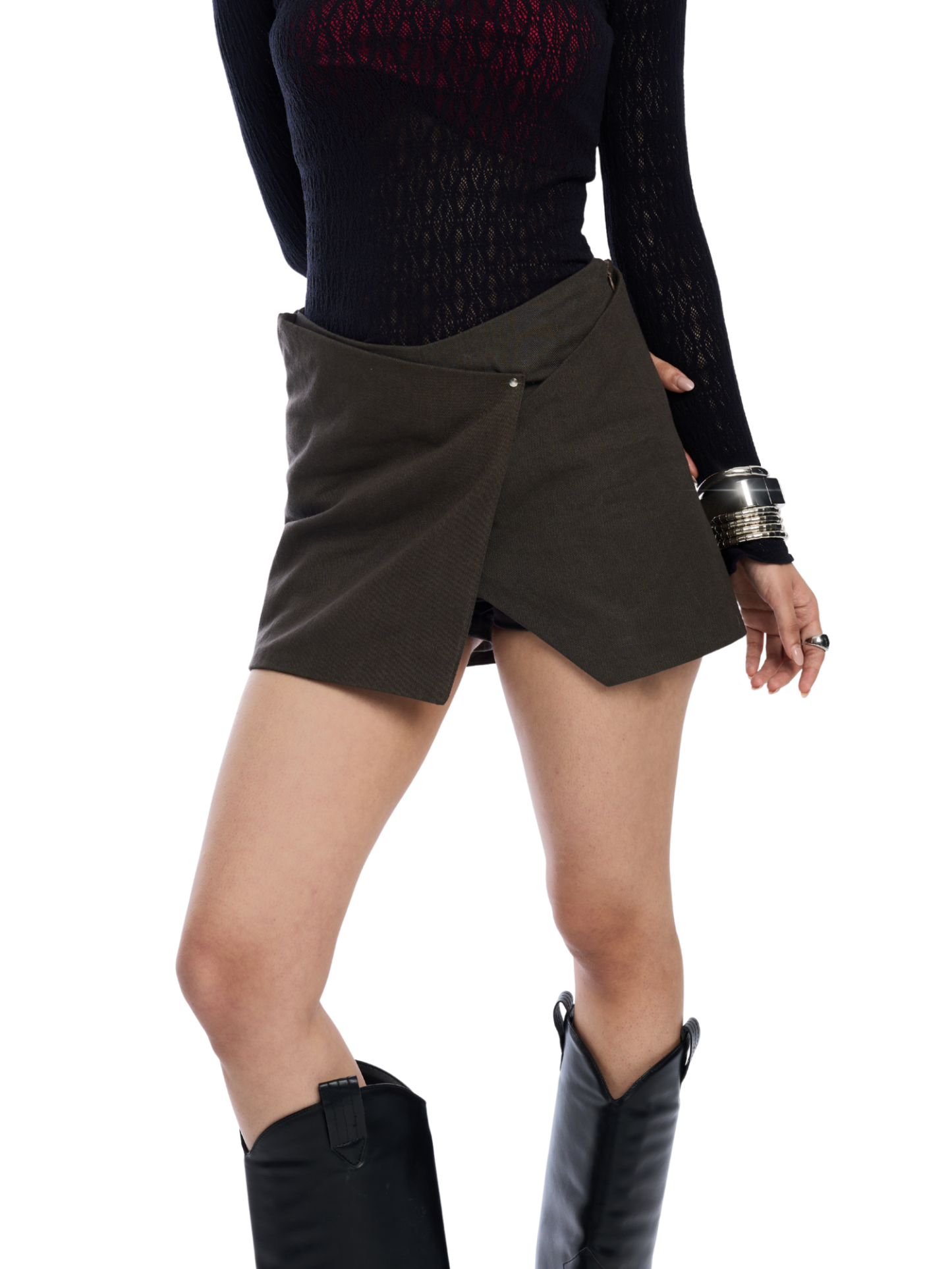 Person wearing a black top and green skirt with black boots on a white background