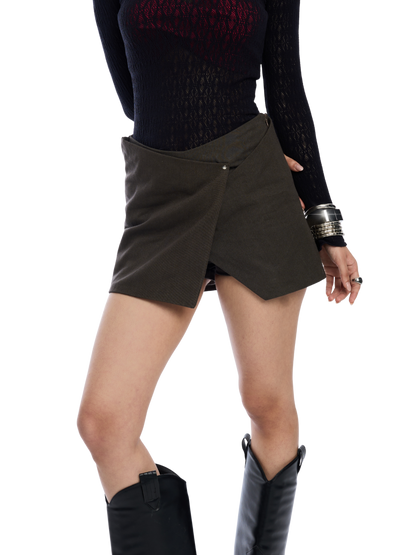 Person wearing a black top and green skirt with black boots on a white background